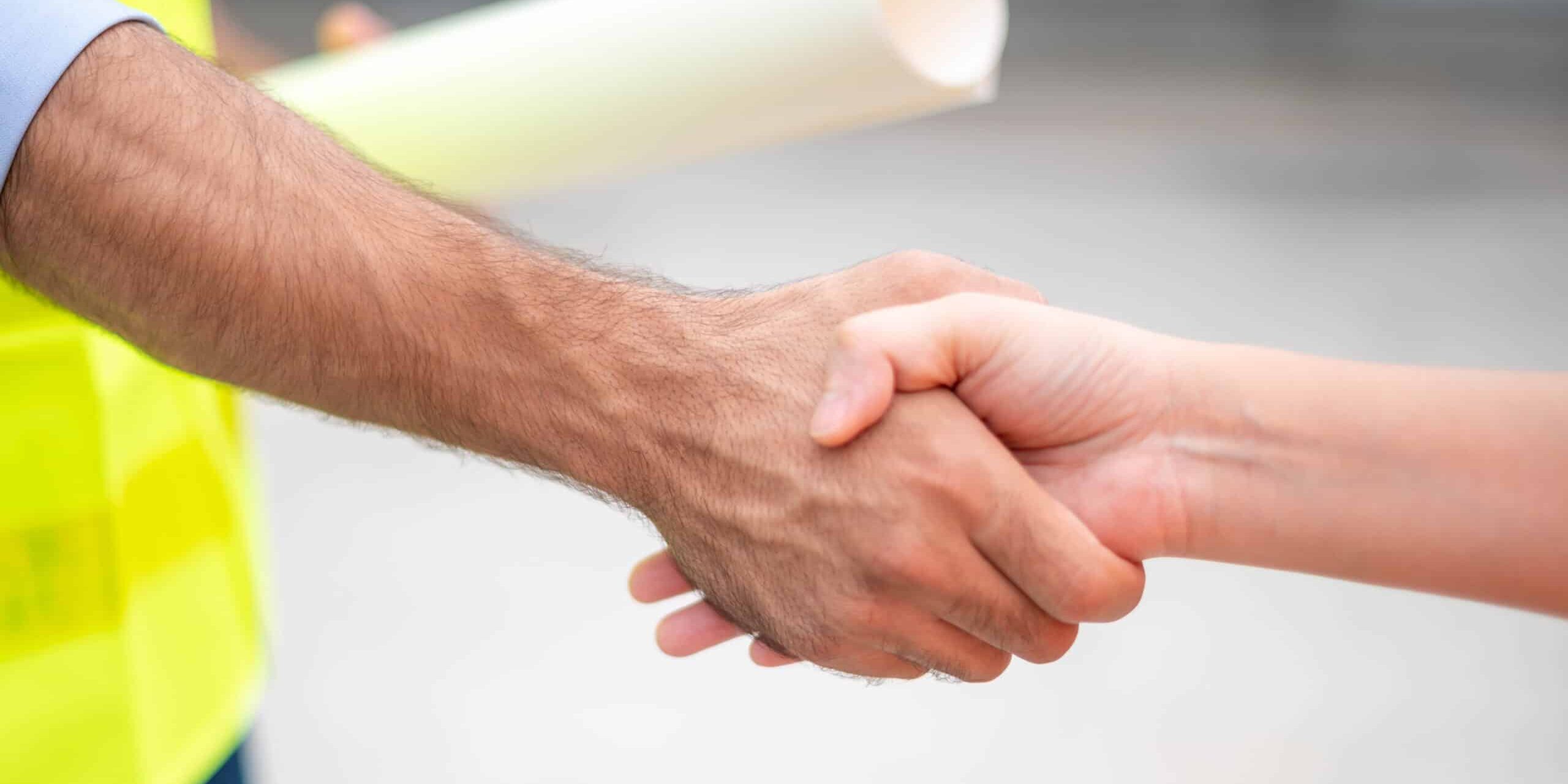 Two engineers shaking hands with deals and success agreements at the construction site. Architect and worker handshaking on construction site. Servpro Partnership - Residential Dumpster Rental St.Louis MO